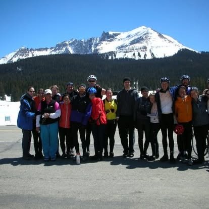 The whole team lined up in front of a snow-covered mountain
