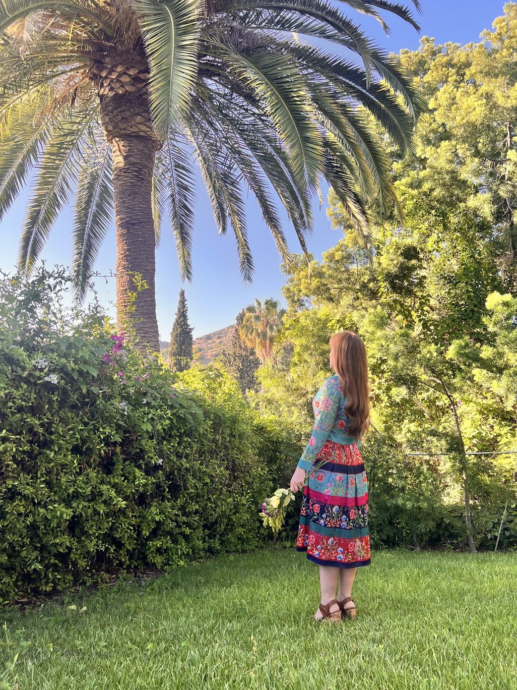 Heather Logghe, MD, seen from behind in a garden beneath a tall palm