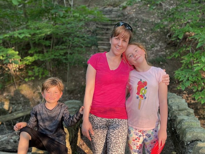 Heather with her two children on a stone wall in the woods